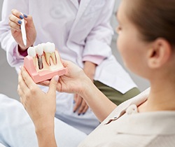 dentist explaining dental implant model to patient 