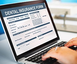 Patient filling out dental insurance form on laptop