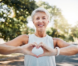 Lady smiles while making shape of heart with her hands