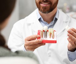 dentist holding dental implant model 