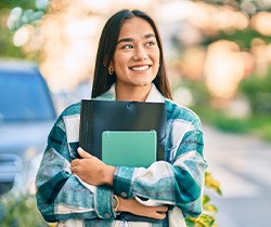 Smiling woman holding books while walking to class