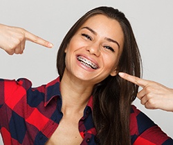Woman with braces in Coppell pointing at smile 