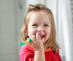 little girl in red shirt holding toothbrush