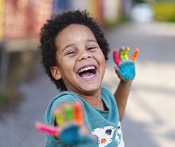 child playing on the sidewalk with painted hands