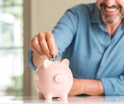 someone smiling and putting money in a piggy bank