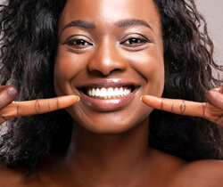 smiling woman pointing to her white teeth