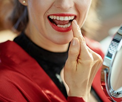 Woman pointing to her new dental crown in Coppell