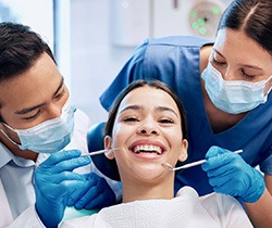 Dentist and dental assistant looking at patient's smile with tools