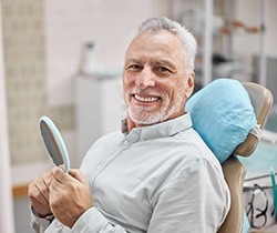 Senior man smiling while holding small mirror