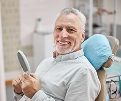 Senior man smiling while holding small mirror
