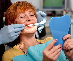 Older woman examining smile in mirror