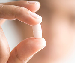 Hand holding white tablet pill