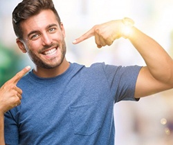 young man pointing to his smile with porcelain veneers in Coppell 