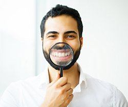 man using magnifying glass to show off results of teeth whitening in Coppell