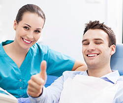 Smiling man in dental chair giving thumbs up