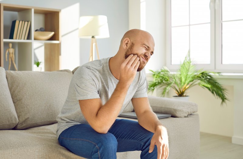 Man holding his jaw due to dental emergencies