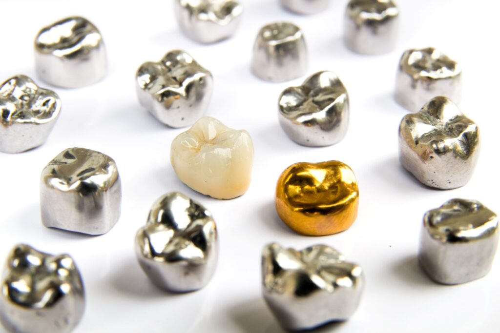 Tooth-colored, gold, and amalgam dental crowns on white surface