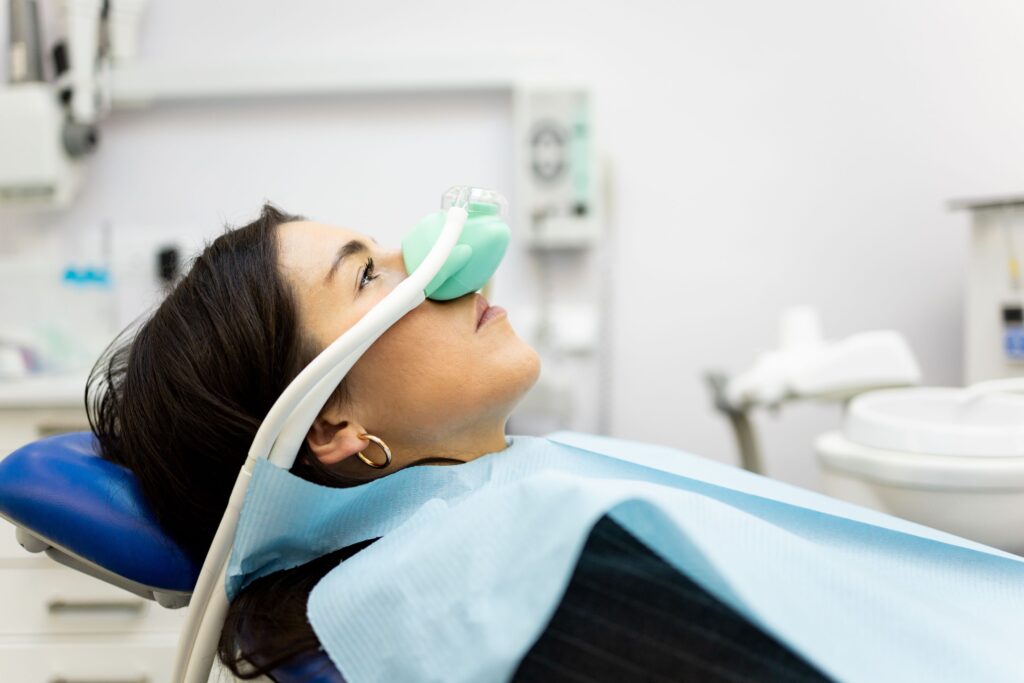 Profile view of woman in dental chair with nitrous oxide mask over nose