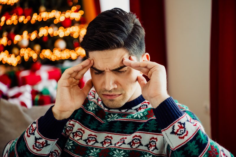 A man in a holiday sweater experiencing holiday stress
